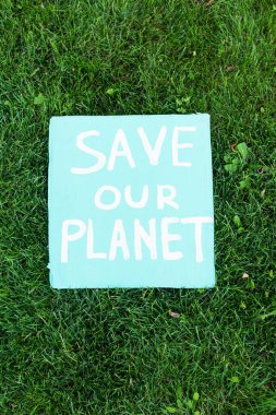 Top view of placard with save our planet lettering on grass, ecology concept clipart