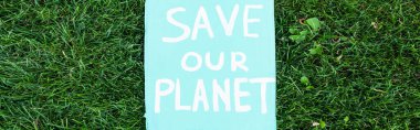 Horizontal concept of placard with save our planet lettering on grass, ecology concept clipart