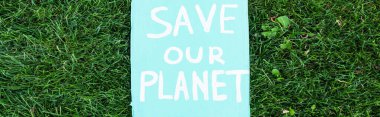 Horizontal concept of placard with save our planet lettering on grass, ecology concept clipart