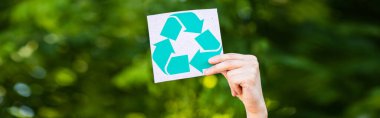 Panoramic crop of man holding card with recycle symbol outdoors, ecology concept clipart