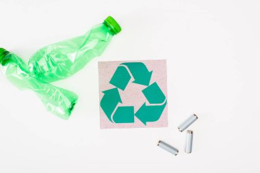 Kırışmış plastik şişeler ve akümülatörlerin yanında geri dönüşüm işareti olan kartın en üst görünümü, ekoloji kavramı