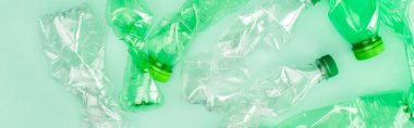 Yeşil yüzeyde buruşmuş plastik şişelerin yatay mahsulü, ekoloji kavramı
