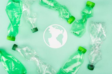 Kağıt gezegen manzarası yeşil yüzeyde buruşmuş plastik şişelerin yanında, ekoloji kavramı