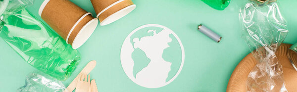 Панорамная ориентация земляных знаков возле одноразовой посуды, пластиковых бутылок и аккумуляторов на зеленом фоне, экологическая концепция