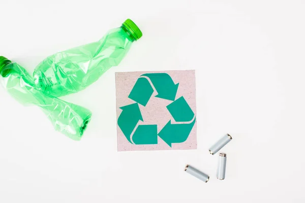 白い背景に砕いたペットボトルやアキュムレータの近くにリサイクルサインのあるカードのトップビュー 生態学的概念 — ストック写真