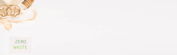 Panoramic shot of card with zero waste lettering near bag, paper cups and cardboard holder on white background, ecology concept