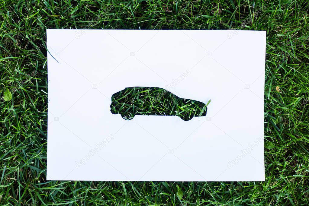 Top view of paper with car sign on green grass, ecology concept