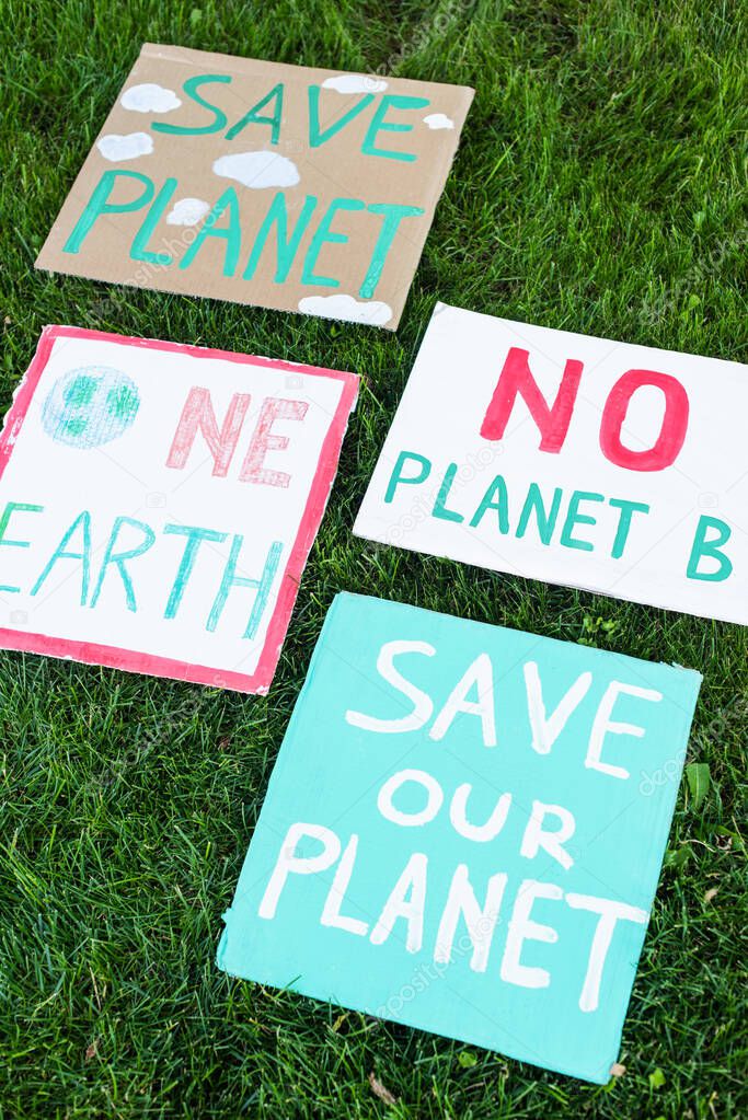 High angle view of placards with no planet b, one earth and save our planet lettering on grass, ecology concept