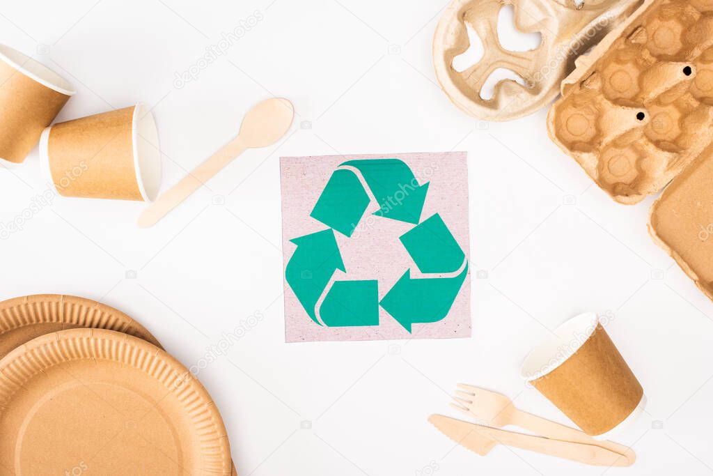 Top view of card with recycle sign near disposable tableware on white background, ecology concept