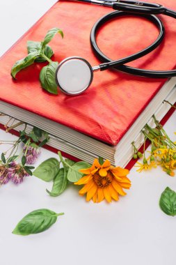 Kitapta steteskoplu bitkiler beyaz arka planda, naturopati konsepti