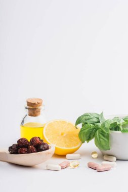 Beyaz arka planda yeşil yapraklar, böğürtlen ve limon yanında haplar, naturopati konsepti