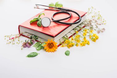 Kitapta steteskoplu bitkiler beyaz arka planda, naturopati konsepti
