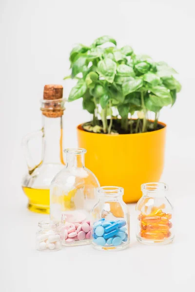 ガラス瓶の中の丸薬の近くの植物の緑の植物の選択的な焦点と白い背景のエッセンシャルオイル 自然障害の概念 — ストック写真