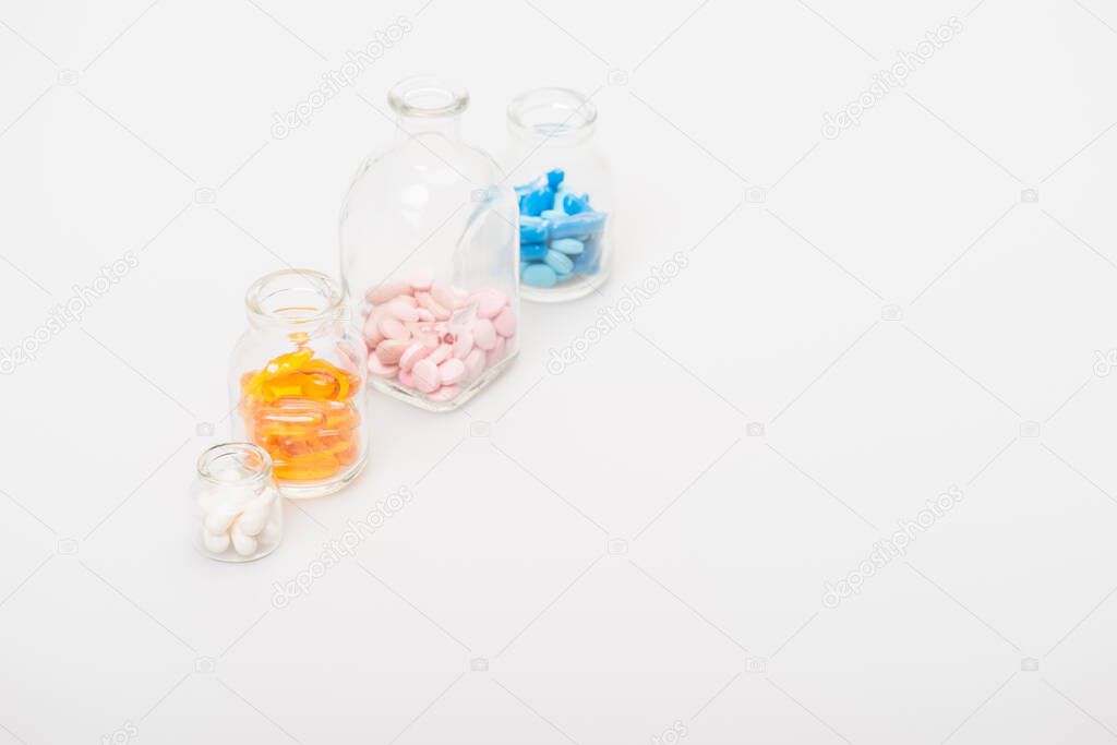 colorful pills in glass bottles on white background
