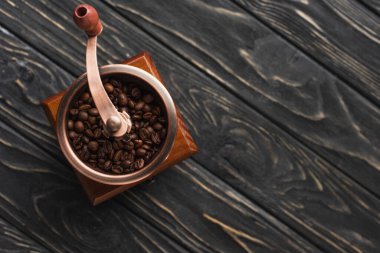 top view of vintage coffee grinder with coffee beans on wooden surface clipart