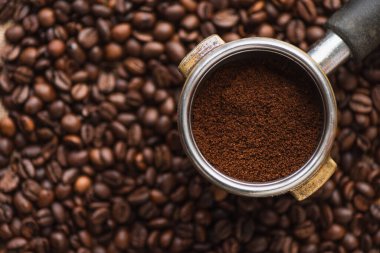 Kahve çekirdeklerinin arka planındaki portafilter 'in en üst görüntüsü.