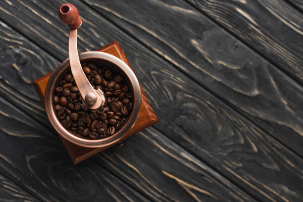 top view of vintage coffee grinder with coffee beans on wooden surface