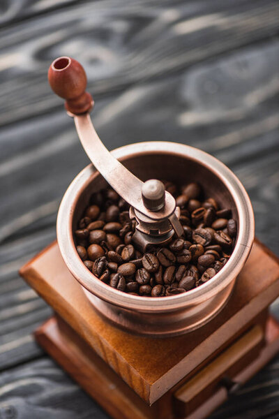 close up view of vintage coffee grinder with coffee beans on wooden surface