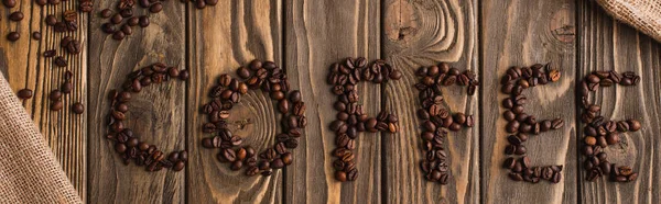 top view of coffee lettering made of beans on wooden surface, panoramic shot