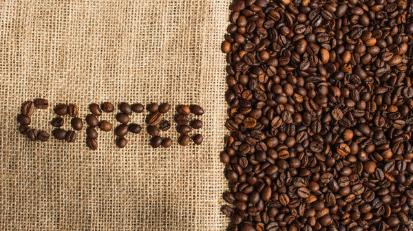 top view of coffee lettering made of beans on sackcloth