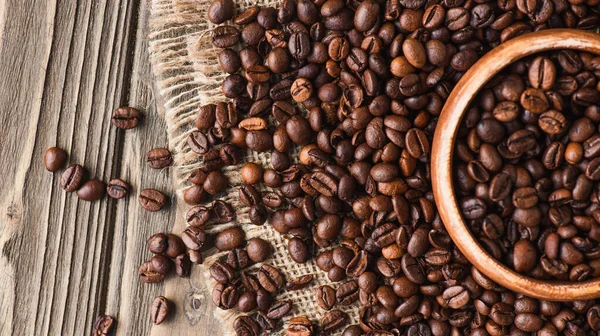 Kahve Çekirdekleri Ahşap Yüzeydeki Kaseden Çuval Bezesine Saçılmış — Stok fotoğraf