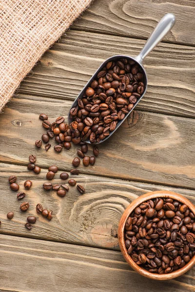咖啡豆和碗放在木制表面的金属勺的顶部视图 — 图库照片