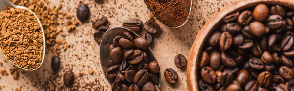 top view of ground, instant coffee and beans in spoons near wooden bowl on beige surface, panoramic shot
