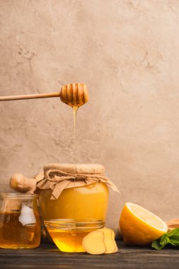 tatlı bal, nane yaprakları, zencefil kökü ve limon bej beton duvarın yanındaki ahşap yüzeyde