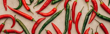 top view of red chili peppers and green jalapenos on beige concrete surface, panoramic shot clipart