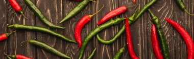top view of red chili peppers and green jalapenos on wooden surface, panoramic shot clipart