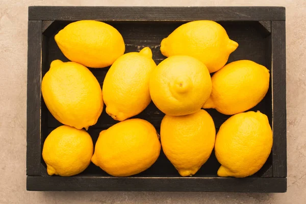 熟した黄色のレモンのトップビューはベージュのコンクリート表面に木製の箱を獲得 — ストック写真
