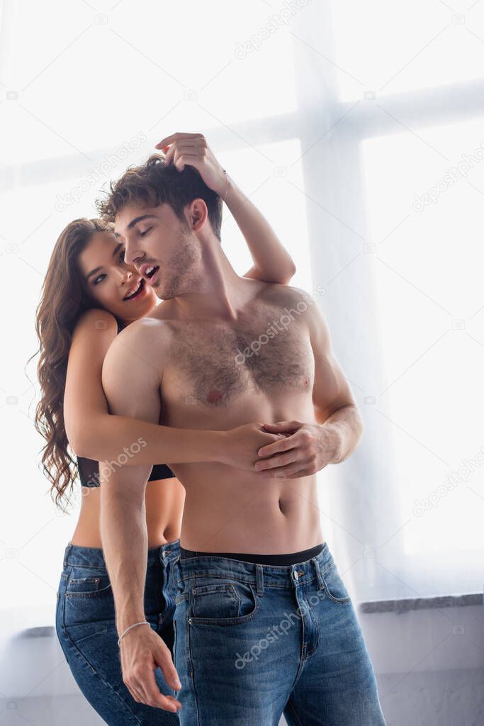 sensual brunette woman hugging shirtless boyfriend 