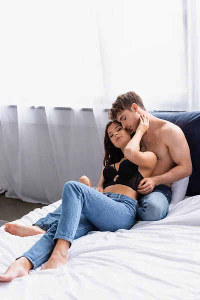 Brunette Woman Bra Jeans Sitting Bed Touching Face Shirtless Man — Stock Photo, Image