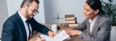 panoramic concept of businessman in glasses signing insurance policy contract near lawyer  clipart