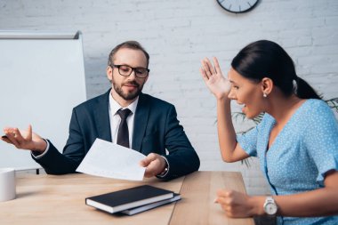 Gözlüklü, sakallı bir avukatın yanında el kol hareketi yapan ve bağıran hoşnutsuz müvekkilin seçici odağı. 