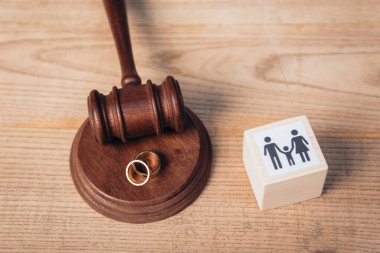 top view of golden rings on gavel near wooden cube with family, divorce concept  clipart