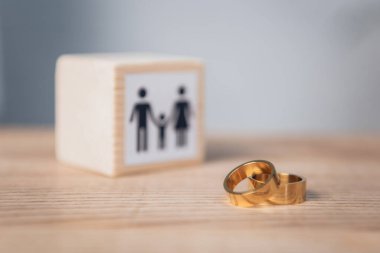 selective focus of golden rings near wooden cube with family  clipart