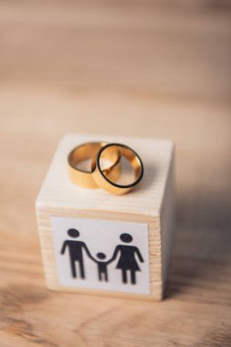 selective focus of golden rings on wooden cube with family  clipart