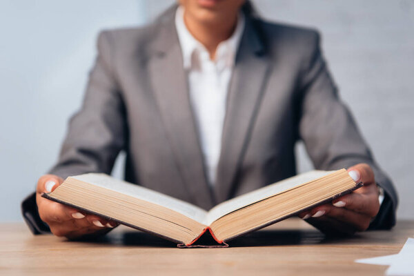 selective focus of lawyer in suit reading book in office