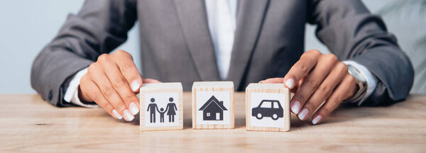 horizontal crop of woman touching wooden cubes with family, car and house 