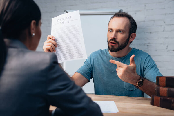 selective focus of bearded man pointing with finger at insurance policy agreement near lawyer 