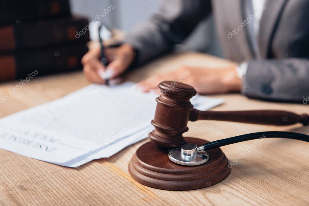 selective focus of gavel and stethoscope near judge signing document 