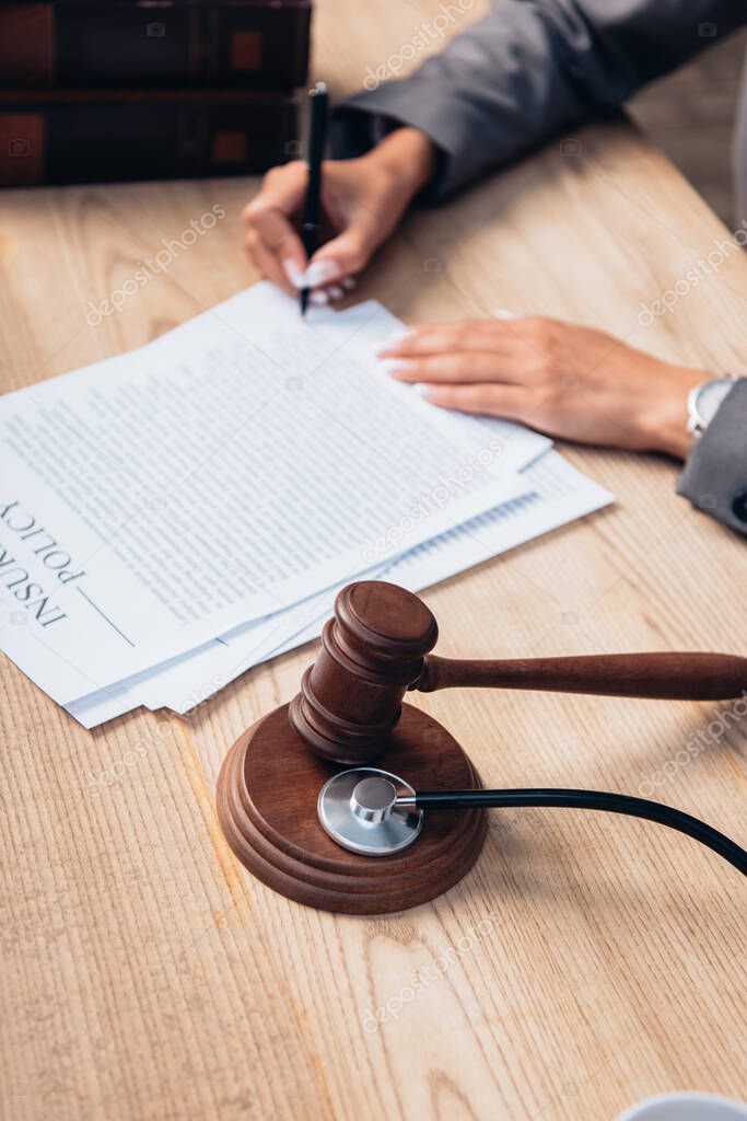 high angle view of gavel and stethoscope near judge signing document 