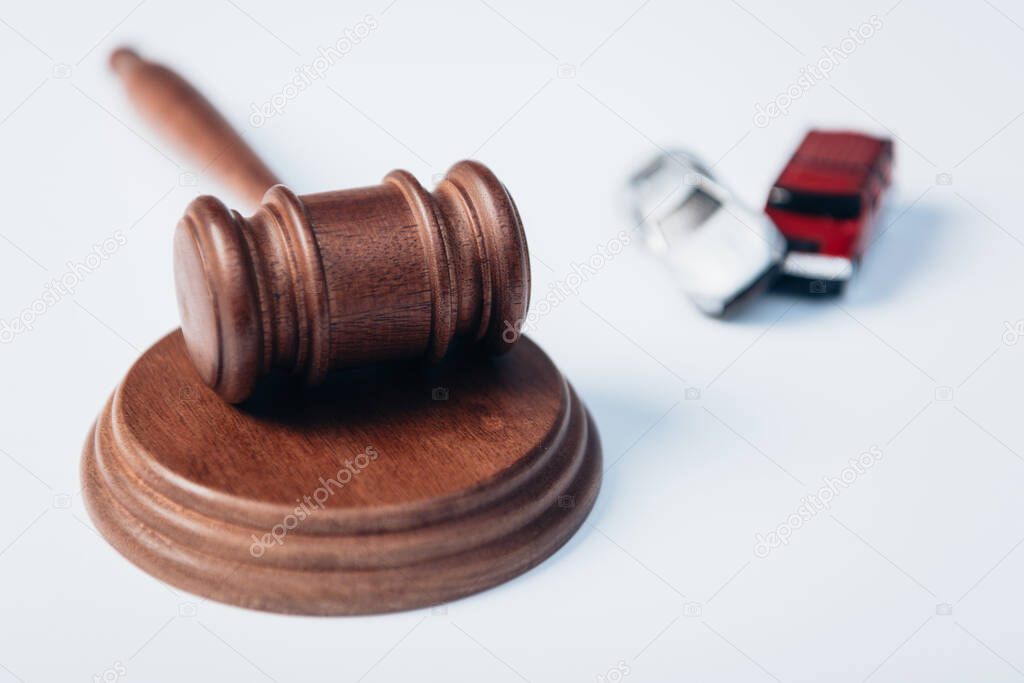 selective focus of gavel near toy cars on white, insurance concept 