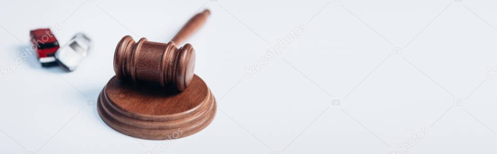 panoramic crop of wooden gavel near toy cars on white, insurance concept 