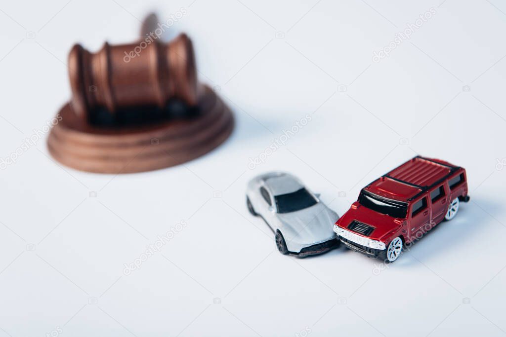 selective focus of toy cars near wooden gavel on white, insurance concept 