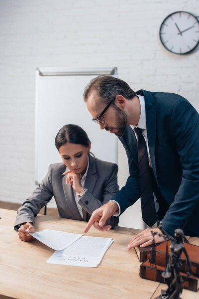 избирательный фокус юриста, указывающего пальцем на документы рядом с предпринимательницей 