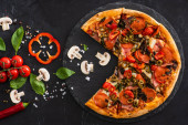 horní pohled na lahodnou italskou pizzu se zeleninou a salámem na černém pozadí