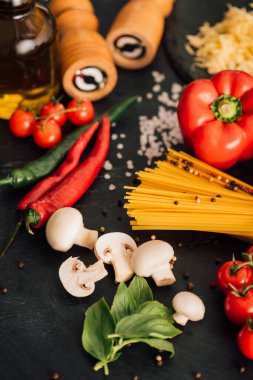 selective focus of raw Italian spaghetti with vegetables on black background clipart