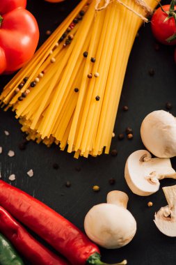 Siyah arka planda sebzeli çiğ İtalyan spagettisinin görüntüsünü kapat.